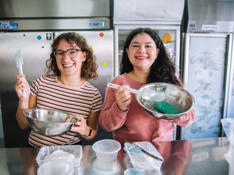Two people smiling while learning how to make macaroons.